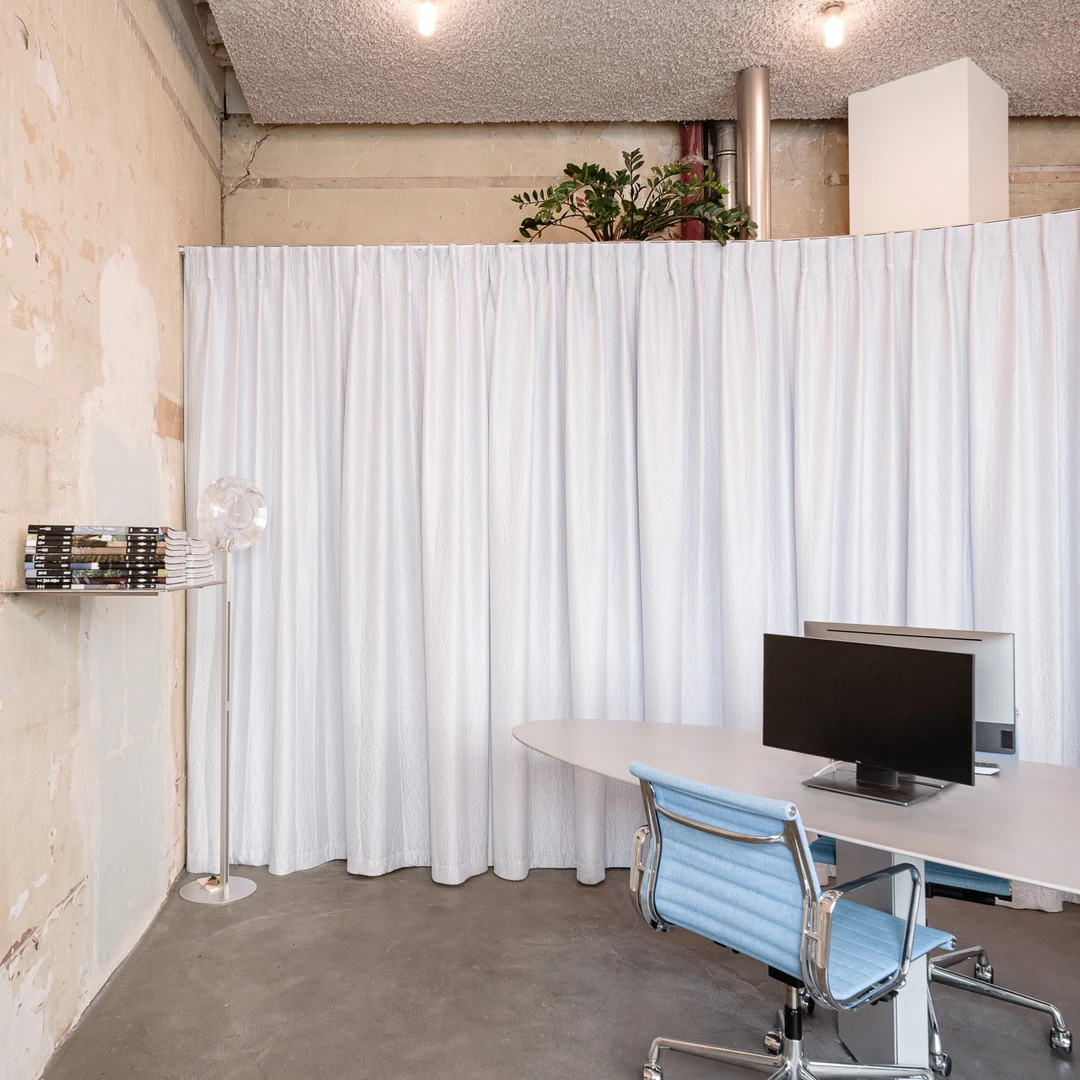Bureau derrière un rideau blanc, mur de pierre et chaise bleue