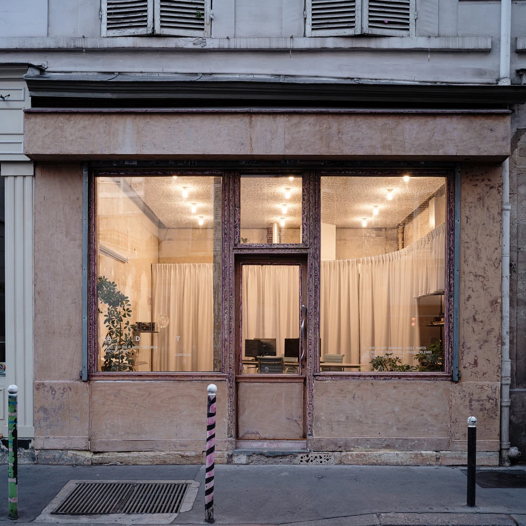 Façade de l’agence, rue Saint-Bernard à Paris : vitrine encadrée de bois et rideaux blancs