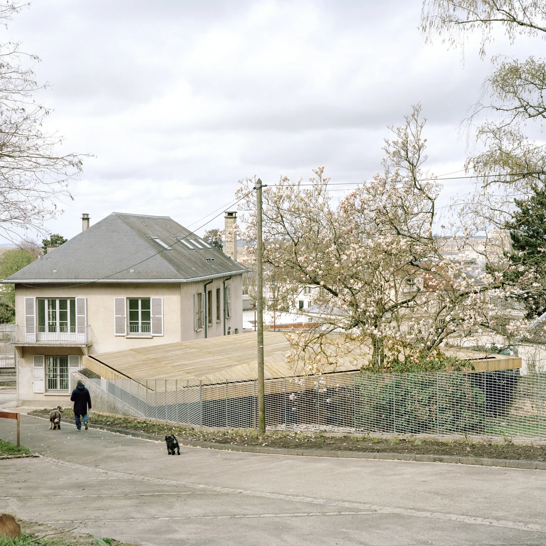 Maison en pierre et pavillon en bois au toit de bardeaux, vue depuis la rue